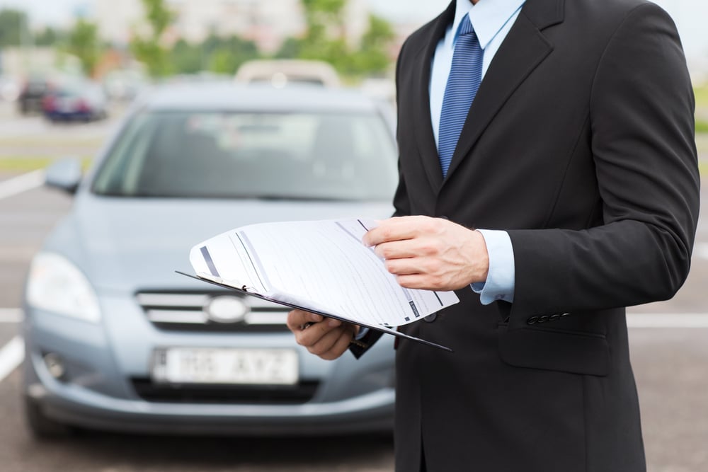 professional inspecting a car with clipboard during vehicle inspection process