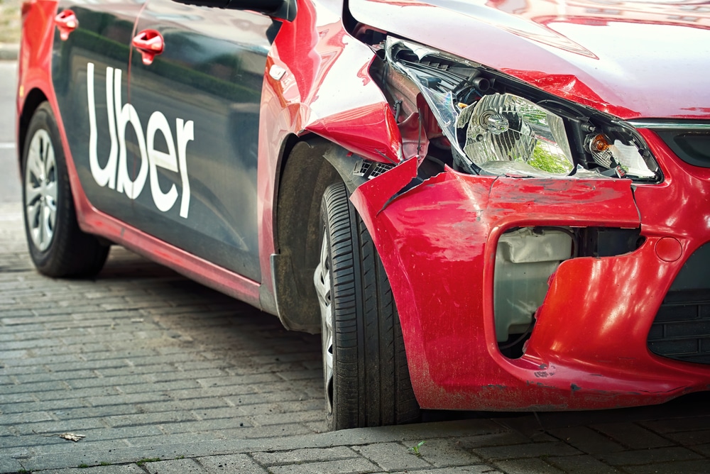 Damaged red Uber vehicle with front-end collision damage after motor vehicle accident in New York