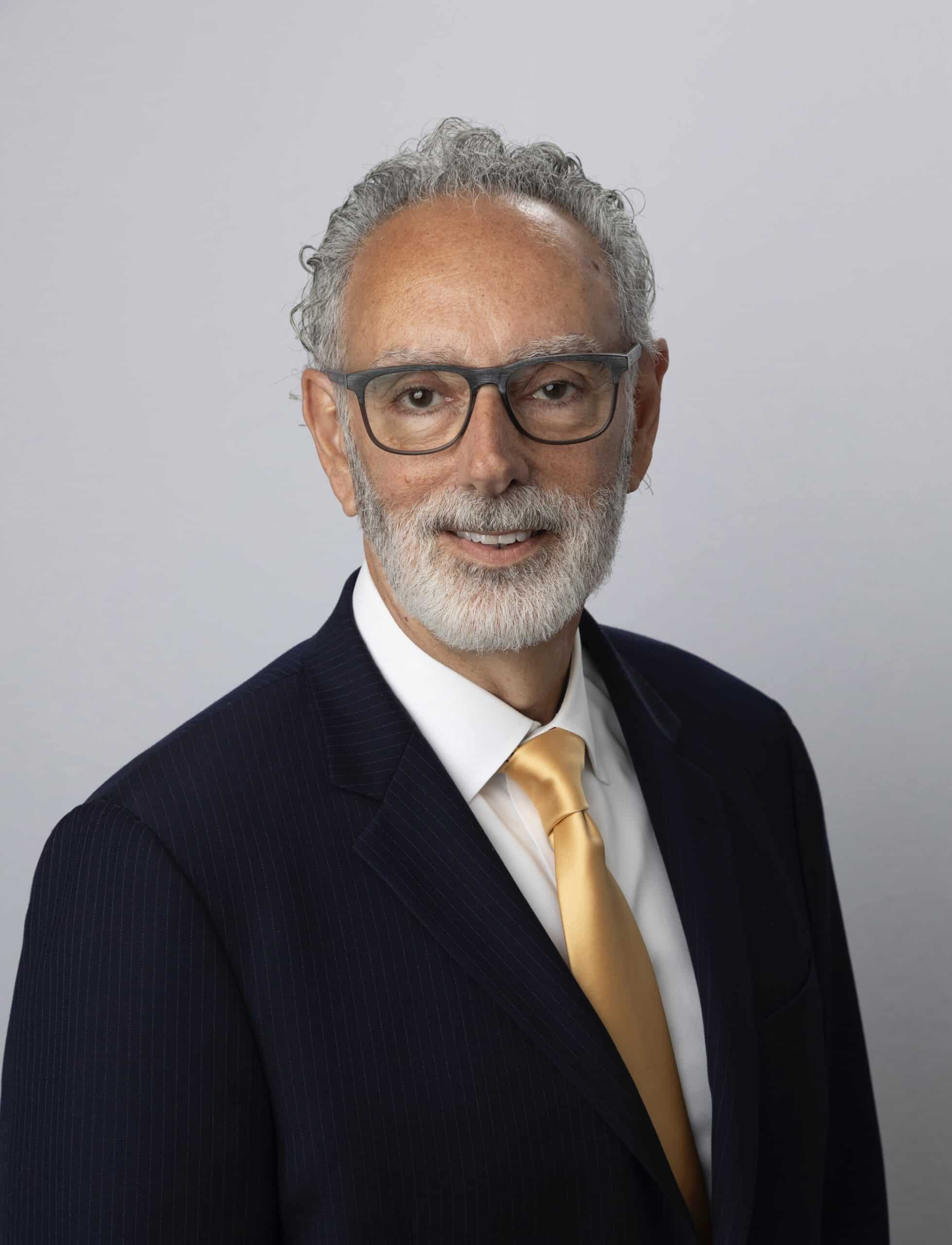 Professional headshot of Elliot Ifraimoff, founder and managing attorney at Elliot Ifraimoff &amp; Associates, PC, wearing glasses and a navy suit with gold tie, specializing in personal injury, car accidents, and construction accidents in New York