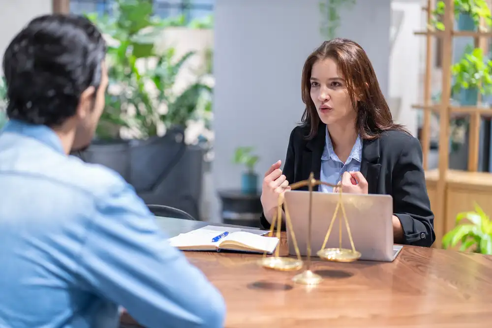 A young lawyer provides dedicated legal advice to a male client during a consultation in a modern law office.